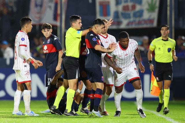 Tigre's midfielder #33 Elias Cabrera (C) pushes America de Cali's defender #02 Marlon Torres (R) past Uruguayan referee Mathias De Armas during the Copa Sudamericana group stage football match between Argentina's Tigre and Colombia's America de Cali at the Jose Dellagiovanna stadium in Victoria, Buenos Aires province, Argentina on April 30, 2026. (Photo by Alejandro PAGNI / AFP)