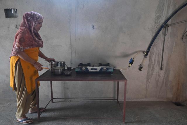This photograph taken on April 24, 2026 shows a villager cooking food using biogas at her residence in Uttar Pradesh's Bulandshahr district. Across much of India, an energy crunch caused by the Iran war has prompted long queues for cooking gas cyclinders. However, since the 1980s India has also promoted biogas as a low-cost rural energy source, subsidising more than five million "digester" units that convert farm waste into methane for cooking, and nitrogen-rich slurry for fertiliser. (Photo by Arun SANKAR / AFP)
