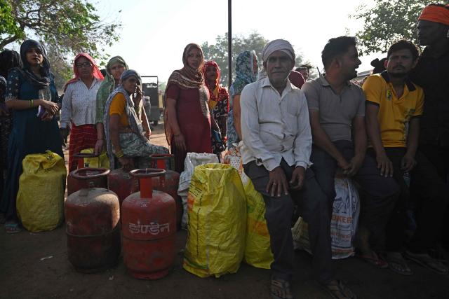 This photograph taken on April 24, 2026 shows people waiting with empty LPG (liquefied petroleum gas) cylinders for refilling, in a village on the outskirts of Uttar Pradesh's Jewar district. Across much of India, an energy crunch caused by the Iran war has prompted long queues for cooking gas cyclinders. However, since the 1980s India has also promoted biogas as a low-cost rural energy source, subsidising more than five million "digester" units that convert farm waste into methane for cooking, and nitrogen-rich slurry for fertiliser. (Photo by Arun SANKAR / AFP)