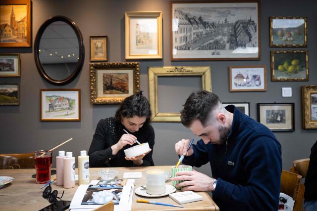 Participants take part in a workshop in a "Cafe ceramique" in Strasbourg, eastern France on April 21, 2026. People come here to switch off from everyday life and their screens, painting a vase or a plate whilst sipping a latte macchiato: riding the wave of the ‘handmade’ trend, ‘ceramics cafes’ are popping up all over France. (Photo by SEBASTIEN BOZON / AFP)
