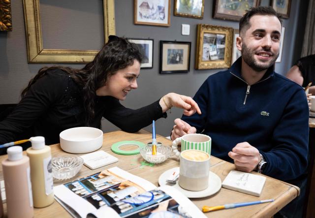Participants take part in a workshop in a "Cafe ceramique" in Strasbourg, eastern France on April 21, 2026. People come here to switch off from everyday life and their screens, painting a vase or a plate whilst sipping a latte macchiato: riding the wave of the ‘handmade’ trend, ‘ceramics cafes’ are popping up all over France. (Photo by SEBASTIEN BOZON / AFP)