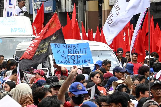 A protester holds a placard during a May Day rally near Malacanang Palace in Manila on May 1, 2026. (Photo by Ted ALJIBE / AFP)