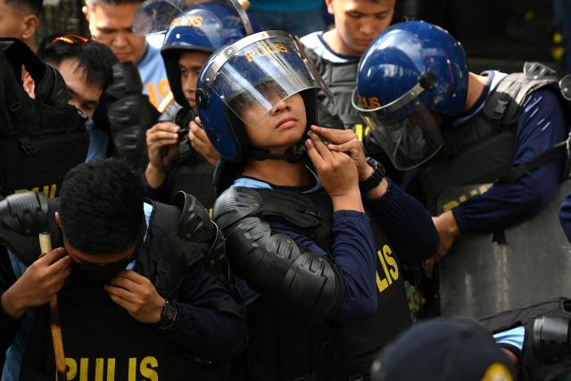 Anti-riot policemen prepare with their gear during a May Day rally near Malacanang Palace in Manila on May 1, 2026. (Photo by Ted ALJIBE / AFP)