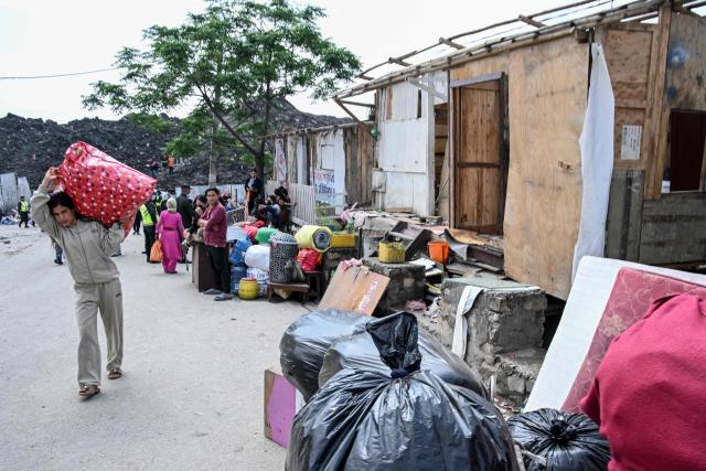 A woman carries her belongings as residents remove household items during the authorities' project to demolish squatter settlements in Kathmandu on May 1, 2026. Nepali authorities has been demolishing informal settlements to thousands of people along river banks of the capital, despite criticism from rights groups. (Photo by PRAKASH MATHEMA / AFP)