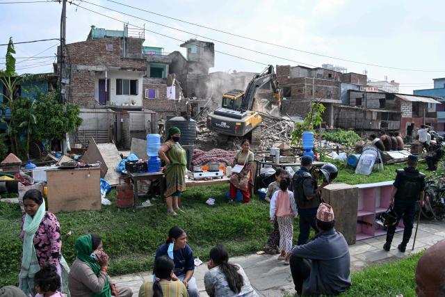 People watch as heavy construction equipment is used to demolish squatter settlements near the Bagmati River in Kathmandu on May 1, 2026. Nepali authorities has been demolishing informal settlements to thousands of people along river banks of the capital, despite criticism from rights groups. (Photo by PRAKASH MATHEMA / AFP)