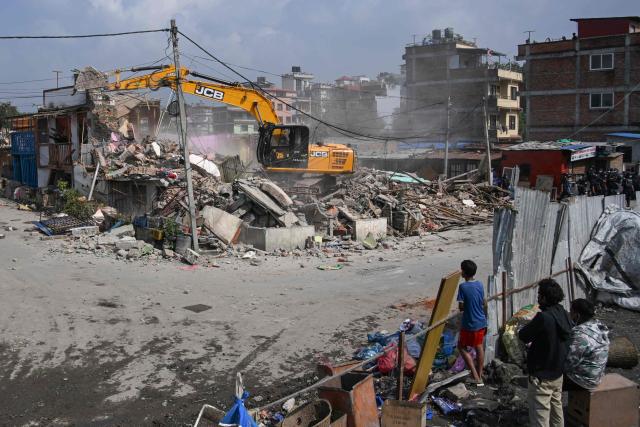 People watch as heavy construction equipment is used to demolish squatter settlements near the Bagmati River in Kathmandu on May 1, 2026. Nepali authorities has been demolishing informal settlements to thousands of people along river banks of the capital, despite criticism from rights groups. (Photo by PRAKASH MATHEMA / AFP)