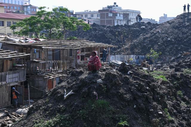 A woman looks on as squatter settlements are demolished near the Bagmati River in Kathmandu on May 1, 2026. Nepali authorities has been demolishing informal settlements to thousands of people along river banks of the capital, despite criticism from rights groups. (Photo by PRAKASH MATHEMA / AFP)