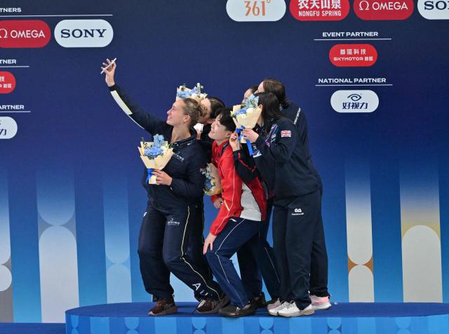 Alysha Koloi of Australia (L) takes a selfie with gold medallists Chen Jia and Chen Yiwen of China (C), silver medallists Maddison Keeney of Australia (L) and bronze medallists Yasmin Harper and Scarlett Mew Jensen of Britain (R) during the medal ceremony for the women's 3m synchronised diving at the World Aquatics Diving World Cup 2026 super finals in Beijing on May 1, 2026. (Photo by ADEK BERRY / AFP)