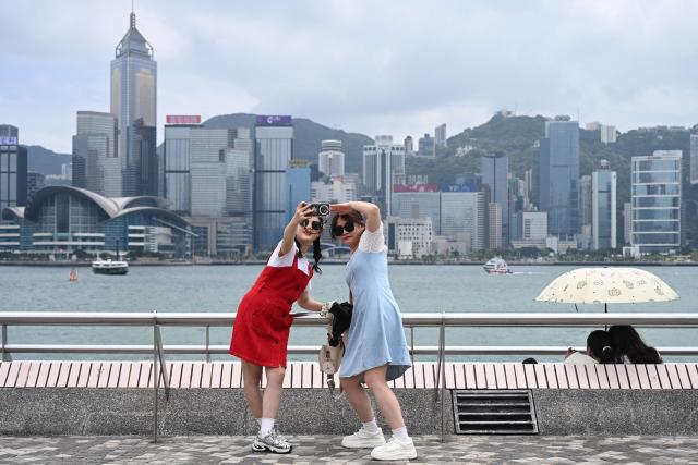 Tourists take photos as they visit Victoria Harbour during China's Labour Day golden week holiday in Hong Kong on May 1, 2026. (Photo by Peter PARKS / AFP)