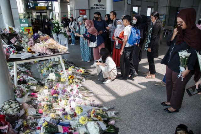 People offer flowers and pray for the victims of a train collision that killed 16 people at Bekasi Timur Station in Bekasi, West Java, on May 1, 2026. A long-distance train slammed into the last, women-only carriage of a stationary commuter train near the Bekasi Timur station late on April 27, prompting a nearly 12-hour rescue effort with crews prying open mangled carriages. (Photo by Aditya Irawan / AFP)