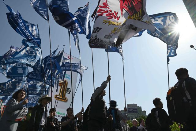 Trade union groups and labour activists carry flags during a Labour Day rally calling for improved working conditions and rights in Seoul on May 1, 2026. (Photo by Jung Yeon-je / AFP)