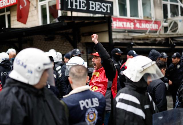 A protestor raises his fist in front of Turkish police officers during a May Day (Labour Day) rally, marking international Workers' Day, in Besiktas, a district of Istanbul, on May 1, 2026. (Photo by BERK OZKAN / AFP)