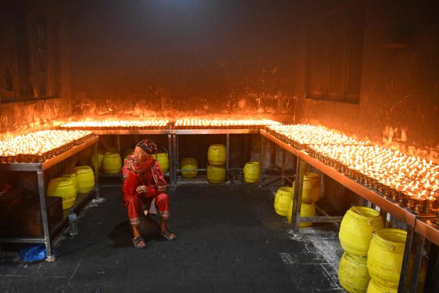 A Buddhist devotee rests after lighting lamps at the Swayambhunath Stupa during Buddha Purnima commemorating Buddha's birthday, in Kathmandu on May 1, 2026. (Photo by PRAKASH MATHEMA / AFP)