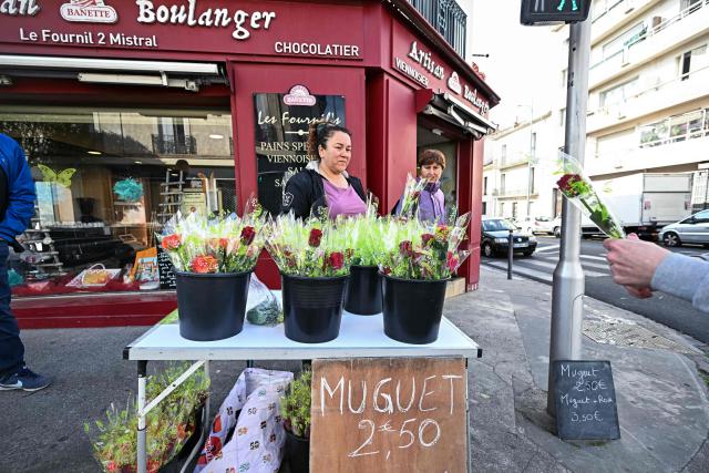 A street vendor sells bouquet of Muguets or Lily of the Valley flowers, a flower used in France to mark May Day (Labour Day), in front of a bakery during International Workers' Day in Beziers, southern France on May 1, 2026.  (Photo by Gabriel BOUYS / AFP)