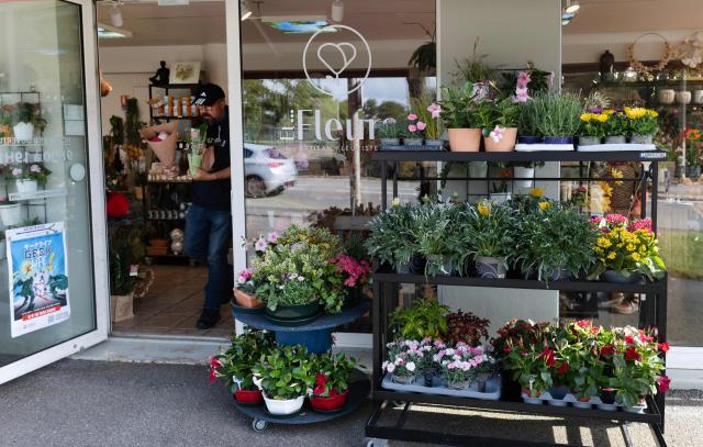 A client walks out of a flower shop in Quimper, western France, on May 1, 2026. The debate over whether independent bakers, florists and other small traders should be allowed to employ staff on May 1 has taken on a national dimension in recent weeks, with the government indicating that bakers and florists may open with their staff as of this year, before a bill formalises the arrangement from next year. (Photo by Fred TANNEAU / AFP)