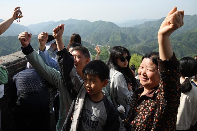 People pose for photos on the Great Wall of China at Badaling, north of Beijing, on May 1, 2026, on the first day of a five-day national May Day holiday. (Photo by GREG BAKER / AFP)