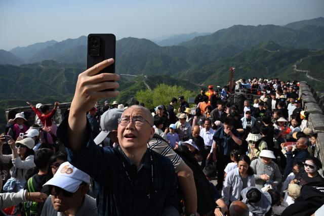A man takes photos on the Great Wall of China at Badaling, north of Beijing, on May 1, 2026, on the first day of a five-day national May Day holiday. (Photo by GREG BAKER / AFP)