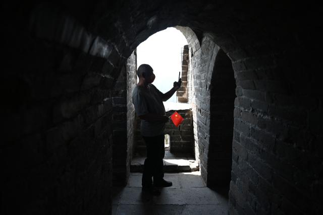 A man takes photos in a watch tower on the Great Wall of China at Badaling, north of Beijing, on May 1, 2026, on the first day of a five-day national May Day holiday. (Photo by GREG BAKER / AFP)