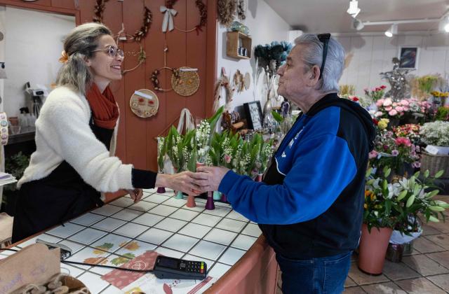 A client purchases a bouquet of lily of the valley in a flower shop in Quimper, western France, on May 1, 2026. The debate over whether independent bakers, florists and other small traders should be allowed to employ staff on May 1 has taken on a national dimension in recent weeks, with the government indicating that bakers and florists may open with their staff as of this year, before a bill formalises the arrangement from next year. (Photo by Fred TANNEAU / AFP)