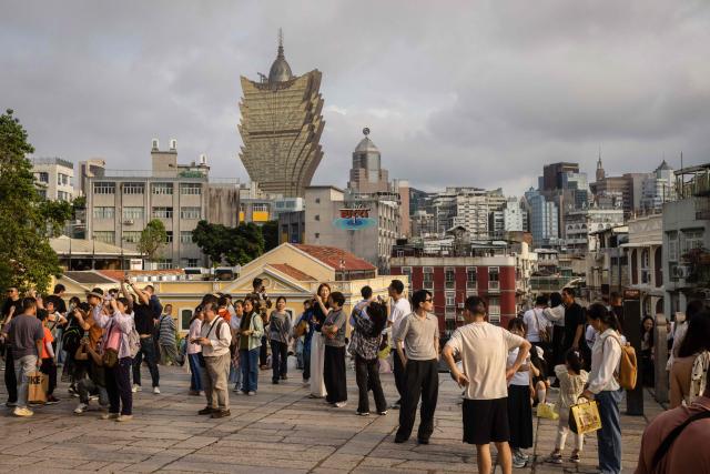 Visitors stand on top of the hill of the Ruins of Saint Paul's with the city skyline behind during the Labour Day holiday in Macau on May 1, 2026. (Photo by Eduardo Leal / AFP)