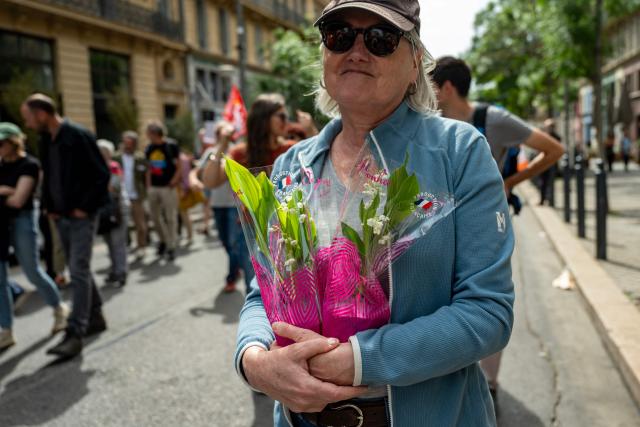 A woman holds bouquets of a lily of the valley during a May Day rally marking International Workers' Day in Marseille, on May 1, 2026. (Photo by MIGUEL MEDINA / AFP)