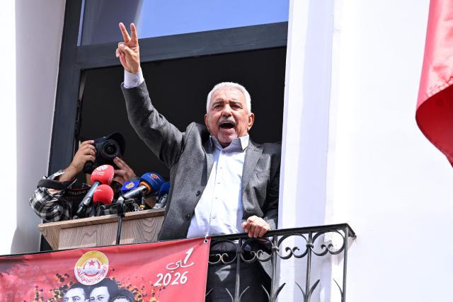 Slaheddine Selmi, the newly elected Secretary General of the Tunisian General Labour Union (UGTT), flashes the V-sign for victory from the balcony of the headquarters during the workers' rally marking May Day, the International Workers' Day, in Tunis on May 1, 2026. (Photo by FETHI BELAID / AFP)