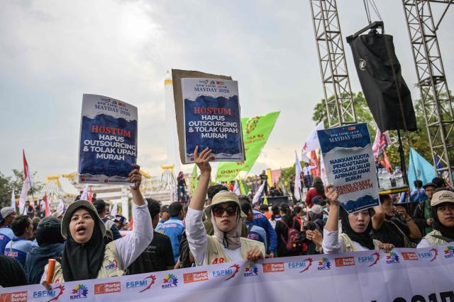 Indonesian workers hold banners reading “End Outsourcing and Reject Low Wages” during a May Day rally marking International Workers' Day in front of the East Java Governor’s Office in Surabaya on May 1, 2026. (Photo by JUNI KRISWANTO / AFP)