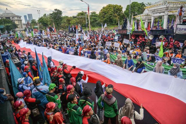 Indonesian workers unfurl the Indonesian flag during a May Day rally marking International Workers' Day in front of the East Java Governor’s Office in Surabaya on May 1, 2026. (Photo by JUNI KRISWANTO / AFP)