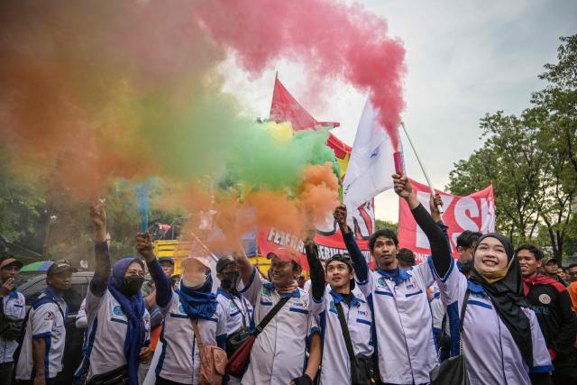 Indonesian workers set off smoke flares during a May Day rally marking International Workers' Day in front of the East Java Governor’s Office in Surabaya on May 1, 2026. (Photo by JUNI KRISWANTO / AFP)