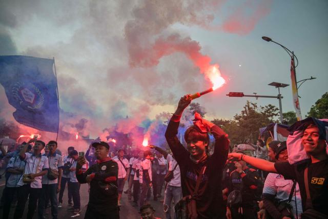 Indonesian workers set off flares during a May Day rally marking International Workers' Day in front of the East Java Governor’s Office in Surabaya on May 1, 2026. (Photo by JUNI KRISWANTO / AFP)