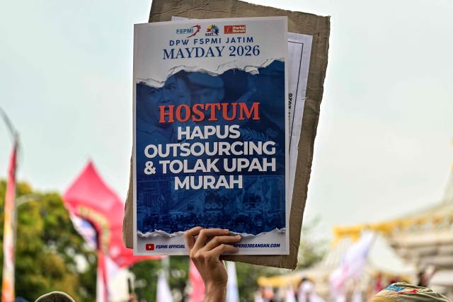 Indonesian worker holds a banner reading “End Outsourcing and Reject Low Wages” during a May Day rally marking International Workers' Day in front of the East Java Governor’s Office in Surabaya on May 1, 2026. (Photo by JUNI KRISWANTO / AFP)