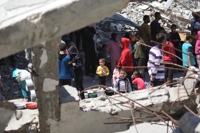 Displaced Palestinians wait amid the rubble of buildings destroyed by the Israeli military to collect food from a charity kitchen in the Bureij refugee camp in the central Gaza Strip on May 1, 2026. The war on the Gaza Strip was sparked following the militant Palestinian group Hamas's October 7, 2023 attack on Israel, which resulted in the deaths of 1,221 people. Israel's retaliatory assault on Gaza has killed at least 72,600 people, according to figures from the health ministry that the UN considers reliable. with th  majority of Gaza's 2.4 million people being displaced. (Photo by Eyad Baba / AFP)