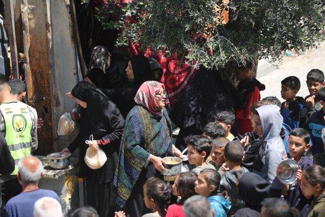 Displaced Palestinians, whose homes were destroyed by the Israeli military, wait to collect food from a charity kitchen in the Bureij refugee camp, in the central Gaza Strip on May 1, 2026. The war on the Gaza Strip was sparked following the militant Palestinian group Hamas's October 7, 2023 attack on Israel, which resulted in the deaths of 1,221 people. Israel's retaliatory assault on Gaza has killed at least 72,600 people, according to figures from the health ministry that the UN considers reliable. with th  majority of Gaza's 2.4 million people being displaced. (Photo by Eyad Baba / AFP)