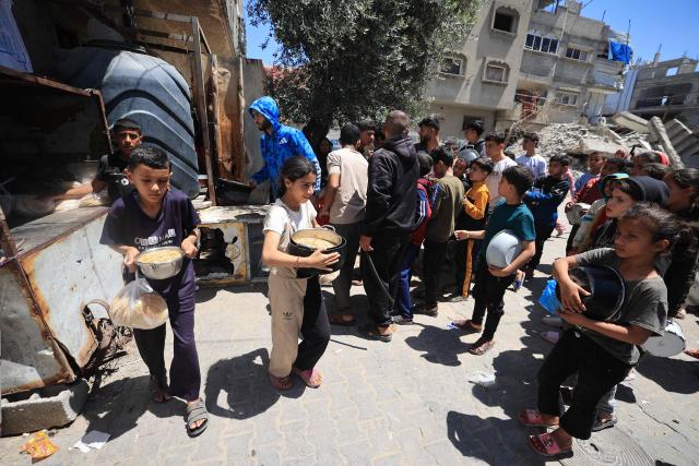 Displaced Palestinians stand near the rubble of buildings destroyed by the Israeli military, as they wait to collect food from a charity kitchen in the Bureij refugee camp, in the central Gaza Strip on May 1, 2026. The war on the Gaza Strip was sparked following the militant Palestinian group Hamas's October 7, 2023 attack on Israel, which resulted in the deaths of 1,221 people. Israel's retaliatory assault on Gaza has killed at least 72,600 people, according to figures from the health ministry that the UN considers reliable. with th  majority of Gaza's 2.4 million people being displaced. (Photo by Eyad Baba / AFP)