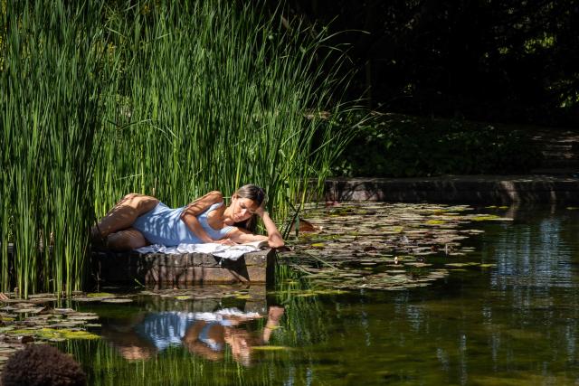A visitor in swimsuit reads a book at the Beyeler Foundation during the experience called "bathers' day" ("journée des baigneurs et des baigneuses") inspired by Italian artist Maurizio Cattelan, on the occasion of the exhibition "Cezanne" of the French painter Paul Cezanne at the Beyeler Foundation in Riehen, northern Switzerland on May 1, 2026. (Photo by SEBASTIEN BOZON / AFP)