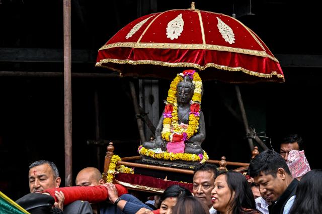 Devotees carry a sculpture of the lord Buddha to be reinstalled at a temple in Kathmandu on May 1, 2026. A centuries-old sculpture of lord Buddha was re-installed at its rightful home in the Nepali capital Kathmandu on May 1, decades after it was stolen and later emerged in the United States. (Photo by Prakash MATHEMA / AFP)
