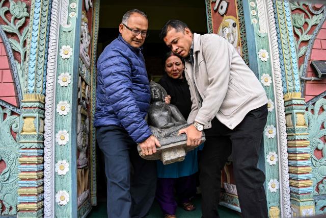 Museum officials and devotees carry a sculpture of the Buddha to be reinstalled at a temple in Kathmandu on April 30, 2026. A centuries-old sculpture of lord Buddha was re-installed at its rightful home in the Nepali capital Kathmandu on May 1, decades after it was stolen and later emerged in the United States. (Photo by Prakash MATHEMA / AFP)