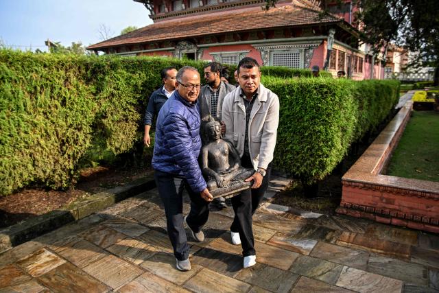 Museum officials and devotees carry a sculpture of the Buddha to be reinstalled at a temple in Kathmandu on April 30, 2026. A centuries-old sculpture of lord Buddha was re-installed at its rightful home in the Nepali capital Kathmandu on May 1, decades after it was stolen and later emerged in the United States. (Photo by Prakash MATHEMA / AFP)