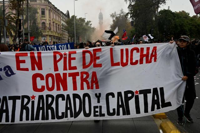 Workers hold a banner reading "Standing in struggle against patriarchy and capital" during a May Day rally demanding better working conditions and pensions, marking International Workers Day, in Caracas, on May 1, 2026. (Photo by RODRIGO ARANGUA / AFP)