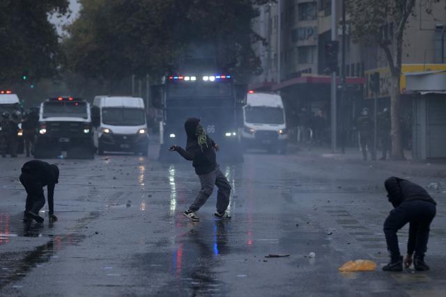 A demonstrator throws stones at riot police during a march organized by unions and social organizations on May Day, marking International Workers Day, in Santiago, on May 1, 2026 (Photo by Rodrigo ARANGUA / AFP)