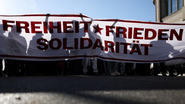 The shadows of participants are seen behind a banner with the lettering 'Freedom, Peace, Solidarity' during the annual leftist May Day demonstration at Oranienplatz Square in Berlin's Kreuzberg district on May 1, 2026. (Photo by Odd ANDERSEN / AFP)
