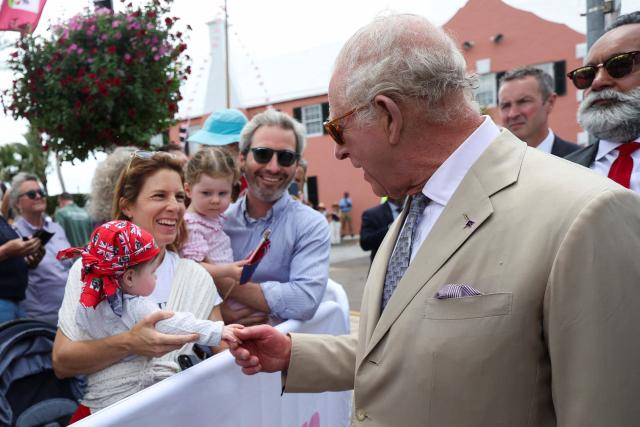 Britain's King Charles holds a baby's hand as he greets supporters during his visit in Hamilton, Bermuda, May 1, 2026. King Charles III is in Bermuda for his first visit to a British Overseas Territory as Sovereign. (Photo by Suzanne Plunkett / POOL / AFP)