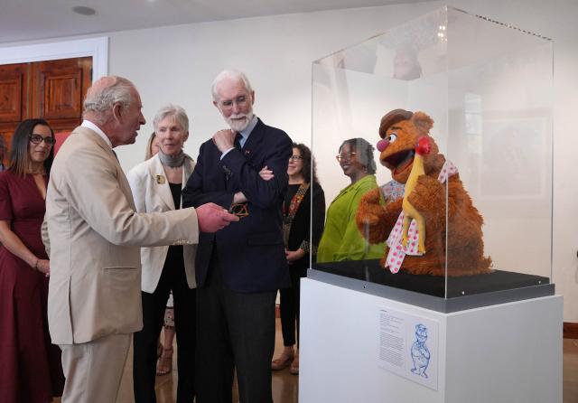 Britain's King Charles III (C) meets Bermuda-born Michael Frith (R), designer of the Muppets, Fraggle Rock and Dr. Seuss, and his wife Kathryn Mullen (C), at the City Hall and Arts Centre, on May 1, 2026 in Hamilton, Bermuda. King Charles III is in Bermuda for his first visit to a British Overseas Territory as Sovereign. (Photo by Yui Mok / POOL / AFP)