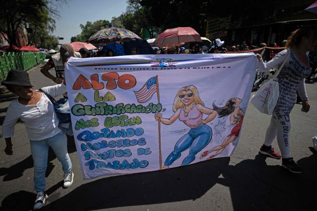 Sex workers hold a banner reading "Stop gentrification, they are taking away our work areas" as they protest for better working conditions amid restrictions linked to the upcoming FIFA 2026 World Cup imposed by the Mexican government, in Mexico City, on International Workers Day, on May 1, 2026. (Photo by CARL DE SOUZA / AFP)