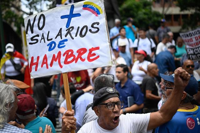 A man holds a sign reading "No more starvation wages" during a May Day rally demanding better working conditions and pensions, marking International Workers Day, in Caracas, on May 1, 2026. (Photo by Federico PARRA / AFP)