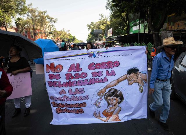 Sex workers hold a banner reading "No to criminal extortion of fellow sex workers" as they protest for better working conditions amid restrictions linked to the upcoming FIFA 2026 World Cup imposed by the Mexican government, in Mexico City, on International Workers Day, on May 1, 2026. (Photo by CARL DE SOUZA / AFP)