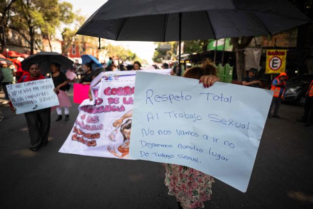 A sex worker holds a sign reading "Full respect for sex work, we will not leave, we will not give up our workplace" as she protests for better working conditions amid restrictions linked to the upcoming FIFA 2026 World Cup imposed by the Mexican government, in Mexico City, on International Workers Day, on May 1, 2026. (Photo by CARL DE SOUZA / AFP)