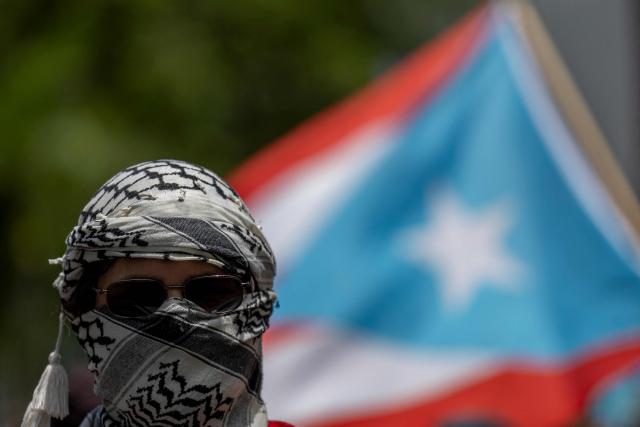 A demonstrator wearing a keffiyeh takes part in a May Day rally marking International Workers' Day in San Juan, Puerto Rico on May 1, 2026. (Photo by Ricardo ARDUENGO / AFP)
