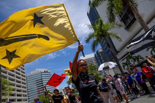 A woman waves a pro-independence movement flag as people take part in a May Day rally marking International Workers' Day in San Juan, Puerto Rico on May 1, 2026. (Photo by Ricardo ARDUENGO / AFP)