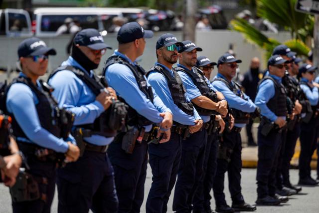 Puerto Rico's police officers stand guard as people take part in a May Day rally marking International Workers' Day in San Juan, Puerto Rico on May 1, 2026. (Photo by Ricardo ARDUENGO / AFP)